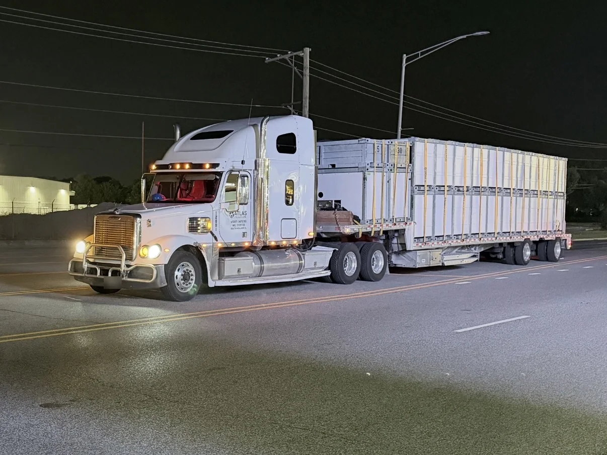 White Atlas Freight Line Freightliner Coronado pulling a loaded flatbed at night